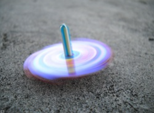 A colourful spinning top on the ground, demonstrating how friction gradually slows its rotation
