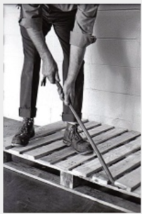 A person using a crowbar to lift a wooden pallet